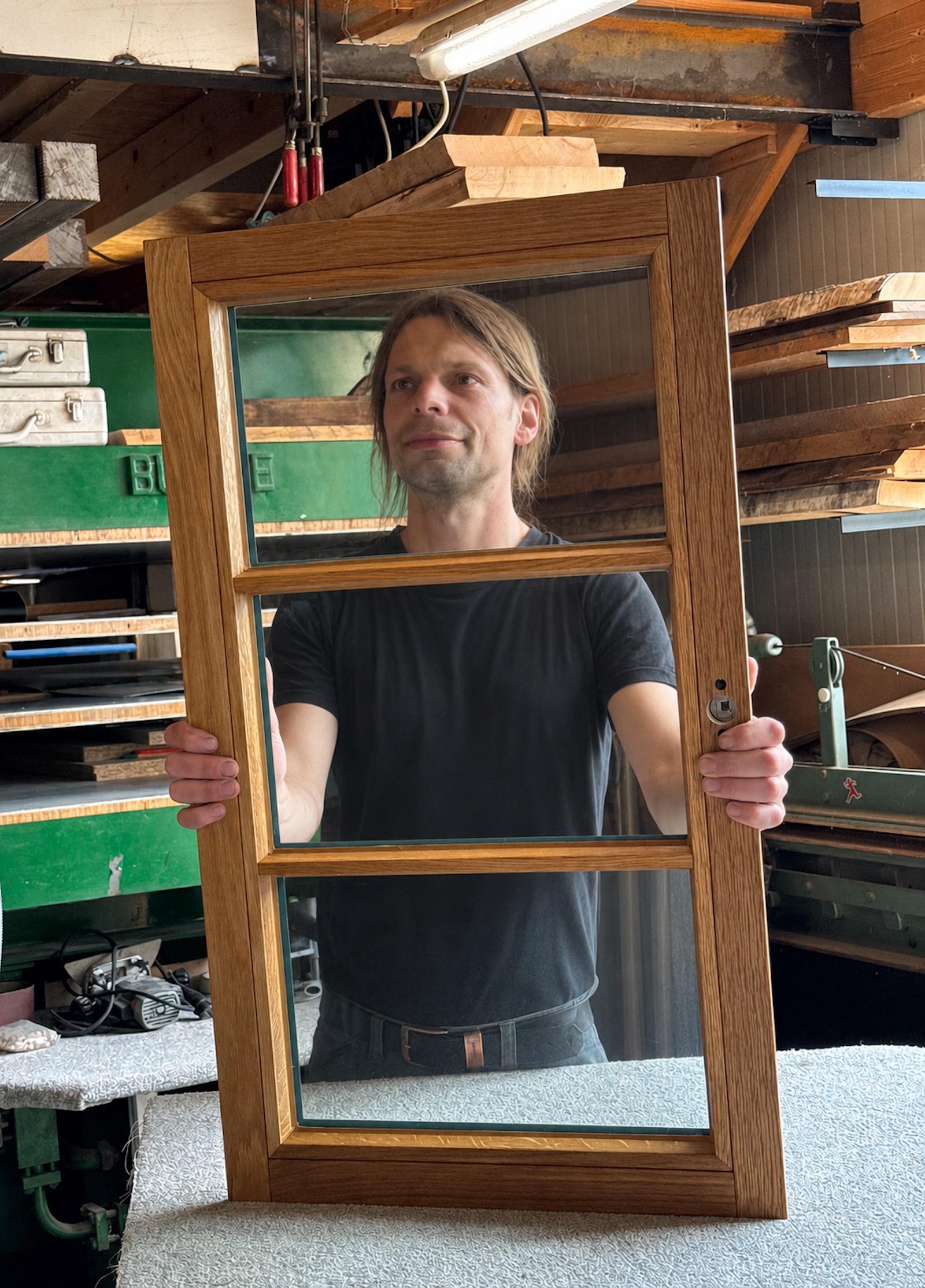 Sebastian Sudhoff bei der Qualitätskontrolle eines handgefertigten Eichenholzfensters